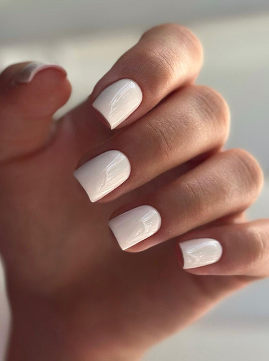 Hand with white nail polish on a neutral background